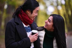 Mixed couple In park enjoying each other and drinking coffee photo