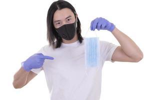 Asian male model wearing and holding surgical face mask and protective gloves photo