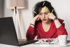 Pretty female model with a lot of post it notes working in her office. photo