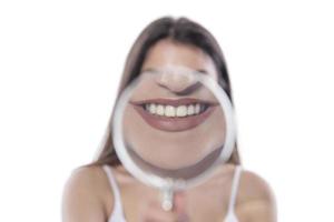 young woman with perfect smile and healthy teeth behind magnifying glass photo
