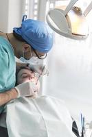 dentist curing patient's teeth filling cavity. Dentist working with professional equipment in clinic. photo