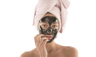 Beautiful girl with black facial cosmetic mask. Beauty concept. isolated photo