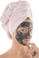 Black facial mask. beautiful girl piling off black mask. beauty concept photo