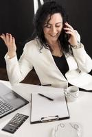 beautiful business woman sitting in her office and talking on the cellphone. business concept photo