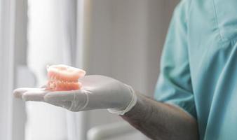 dentist holding ceramic dental prothesis photo
