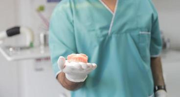 dentist holding ceramic dental prothesis photo