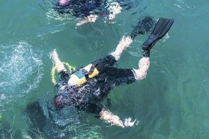 Top view of scuba diver swimming under water and examines the seabed. Scuba diver bubbles coming from bottom to surface. photo