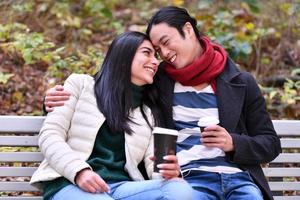 Mixed couple In park enjoying each other and drinking coffee photo