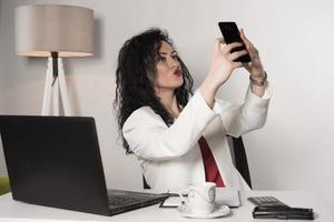 bella mujer de negocios sentada en su oficina y hablando por celular. concepto de negocio foto