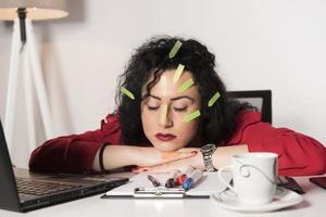 Pretty female model with a lot of post it notes working in her office. photo