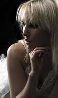 Beautiful blond woman wearing white nightgown posing on black  background. photo