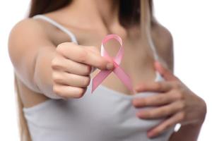 concepto de salud y medicina. mano de mujer con cinta rosa de concientización sobre el cáncer de mama. foto