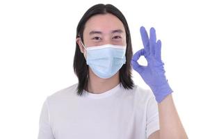 modelo masculino asiático usando y sosteniendo mascarilla quirúrgica y guantes protectores foto