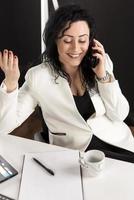 beautiful business woman sitting in her office and talking on the cellphone. business concept photo