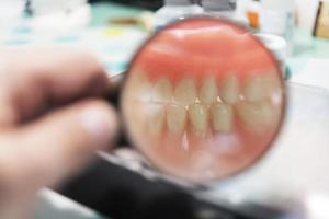 Dental prosthesis, dentures, prosthetics work. Prosthetics hands while working on the denture, false teeth, a study and a table with dental tools photo