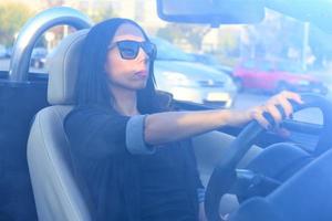 hermosa mujer feliz conduciendo un coche deportivo en la ciudad foto