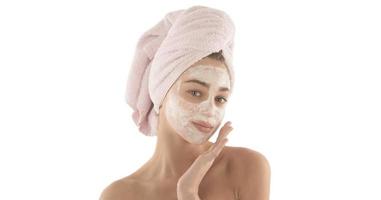 Beauty procedures skin care concept. Young woman applying facial mud clay mask to her face photo