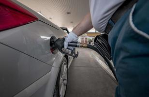 bombeo de gas en la bomba de gas. Primer plano del hombre de bombeo de combustible de gasolina en el coche en la gasolinera. foto