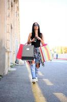 hermosa mujer caminando por la calle con bolsas de compras. modelo femenino de moda en la ciudad con bolsas de compras. foto