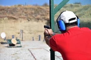 vista trasera de un hombre disparando su arma en un rancho de práctica. foto