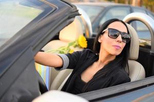 Happy beautiful woman driving a sports car in the city photo