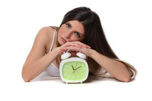 Beautiful sleeping woman resting in bed with alarm clock ready to wake her in the morning. photo