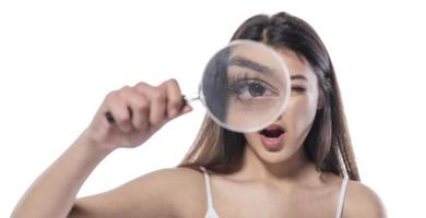 attractive woman looking through magnifying glass photo