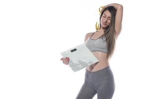 modelo femenino sosteniendo escala y cinta métrica sobre fondo blanco foto