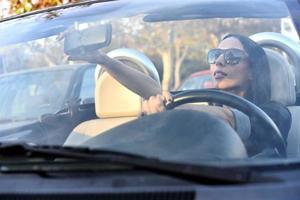 hermosa mujer feliz conduciendo un coche deportivo en la ciudad foto