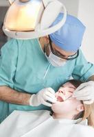 dentist curing patient's teeth filling cavity. Dentist working with professional equipment in clinic. photo