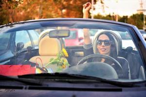 Hermosa mujer feliz conduciendo un auto convertible deportivo en la ciudad foto