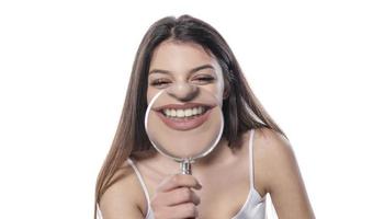 young woman with perfect smile and healthy teeth behind magnifying glass photo