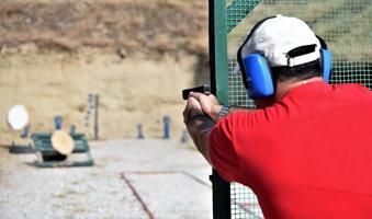 back view of a man shooting his gun on a practice ranch. photo