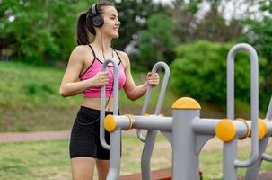 deportista trabajando en el equipamiento deportivo público en el gimnasio al aire libre. una mujer activa deportiva en un parque foto