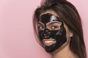 Beautiful smiling woman piling off black mask from her face. Beauty concept. isolated photo