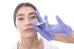 young woman gets injection of botox in her lips. Woman in beauty salon. plastic surgery clinic. photo