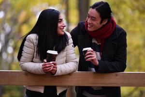 pareja mixta en el parque disfrutando unos de otros y tomando café foto