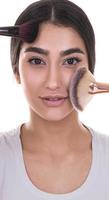 Mixed race woman putting make up on her face with makeup brush photo