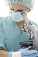 Scientist in blue medical gloves and uniform learning COVID-19 samples with microscope in laboratory. photo