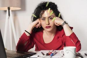 Pretty female model with a lot of post it notes working in her office. photo