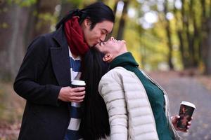 Mixed couple In park enjoying each other and drinking coffee photo