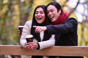 pareja mixta en el parque disfrutando unos de otros y tomando café foto