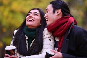 Mixed couple In park enjoying each other and drinking coffee photo