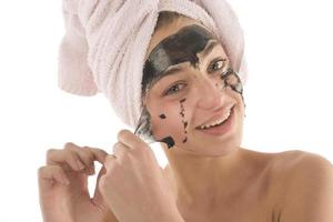 Black facial mask. beautiful girl piling off black mask. beauty concept photo