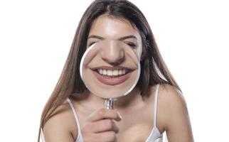 young woman with perfect smile and healthy teeth behind magnifying glass photo