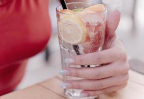 primer plano de una mujer disfrutando de un cóctel mojito tropical decorado con fruta fresca foto