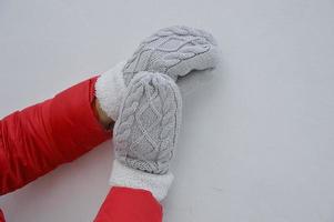 Female hands in light gray knitted mittens with white fur. Protecting hands from the cold. Winter accessories. photo