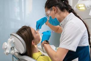 dentista trata los dientes a una niña en una clínica foto