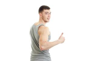 sporty young man with muscles turned his back to the camera smiling and shows the class photo