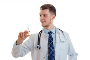 el apuesto joven doctor sonriendo y sosteniendo un primer plano de la vacuna de la jeringa foto